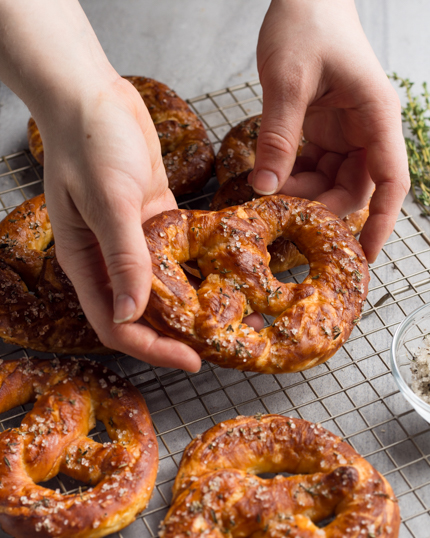 Hands lifting a baked pretzel off a wire rack