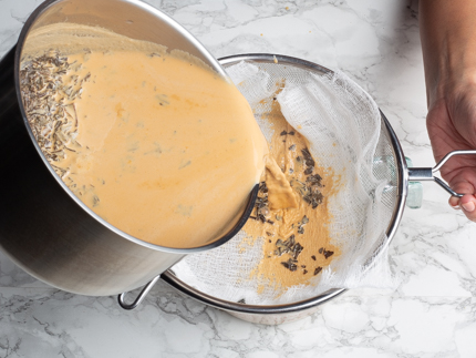 Pouring tea and evaporated milk mixture from a pot into a cheesecloth-lined sieve