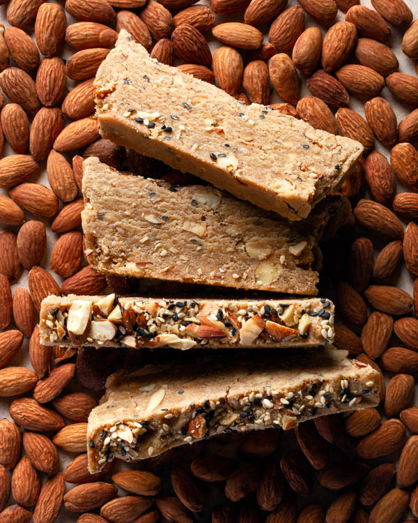 Slices of almond halva on a bed of raw almonds