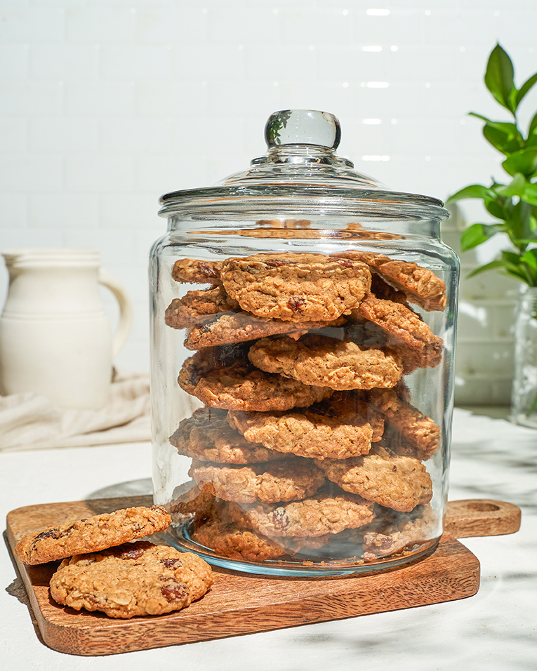 ` A glass jar full of soft oatmeal raisin cookies