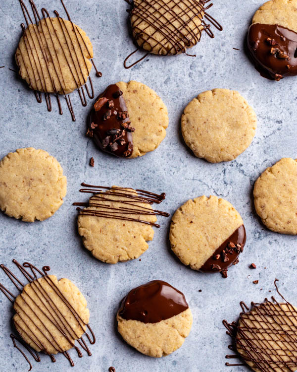 Vegan sugar cookies dipped and drizzled with chocolate on a granite counter