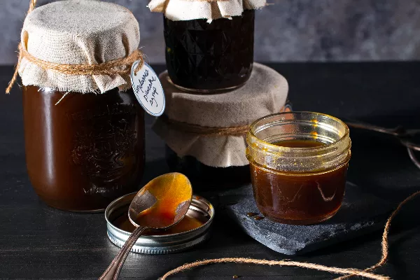 Four jars of molasses pancake syrup, one open with a spoon beside