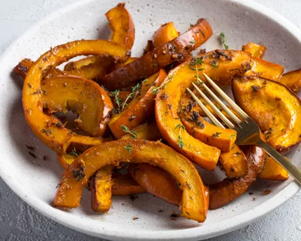 Roasted pumpkin sections in a dish with seasoning