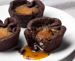 Chocolate Butter Tarts on a plate, one with filling leaking out