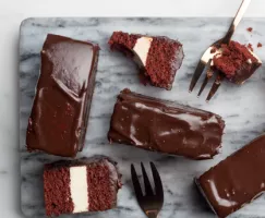 Chocolate dipped red velvet cake bars with forks on a cutting board