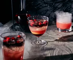 Black vodka and cranberry cocktail on a spooky background with swirling smoke